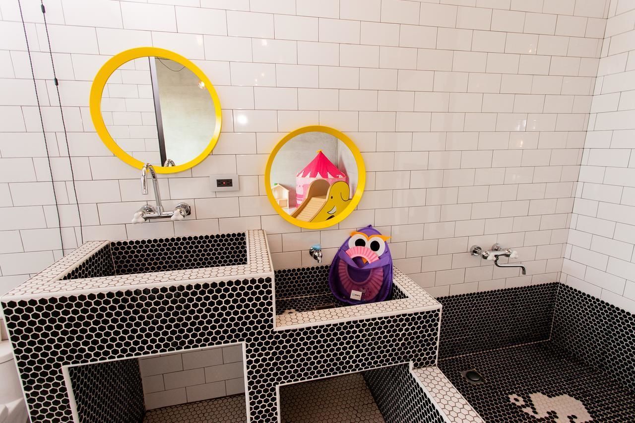 A bathroom with two sinks, each with a mirror, and a shower area with a hexagonal tile pattern.
