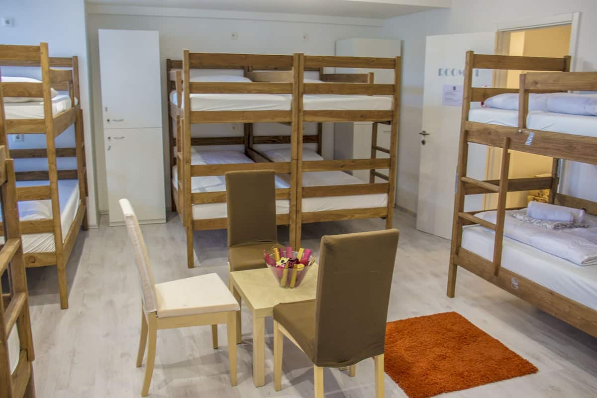 Una camera del dormitorio con letti a castello, un tavolino con sedie e un tappeto.