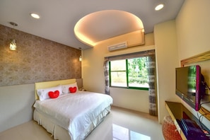 A bedroom with a bed, a TV, and a window.
