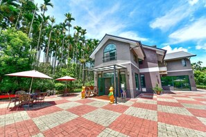 A modern building with a checkered floor, outdoor seating, and a clear sky.