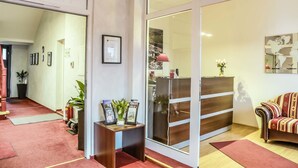 Vestíbulo de hotel con mostrador de recepción, un sofá y un espejo grande que refleja el interior.
