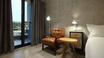 Habitación de hotel con una butaca de cuero, una mesita redonda pequeña, una cama y vistas a través de una puerta corredera.