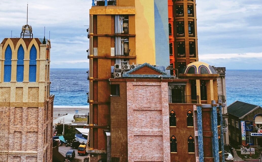 A coastal cityscape with a prominent church tower and a modern building with a yellow facade.