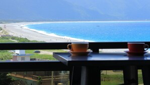A view from a window overlooking a beach with a mountain in the background. - I See U Inn (Xincheng)