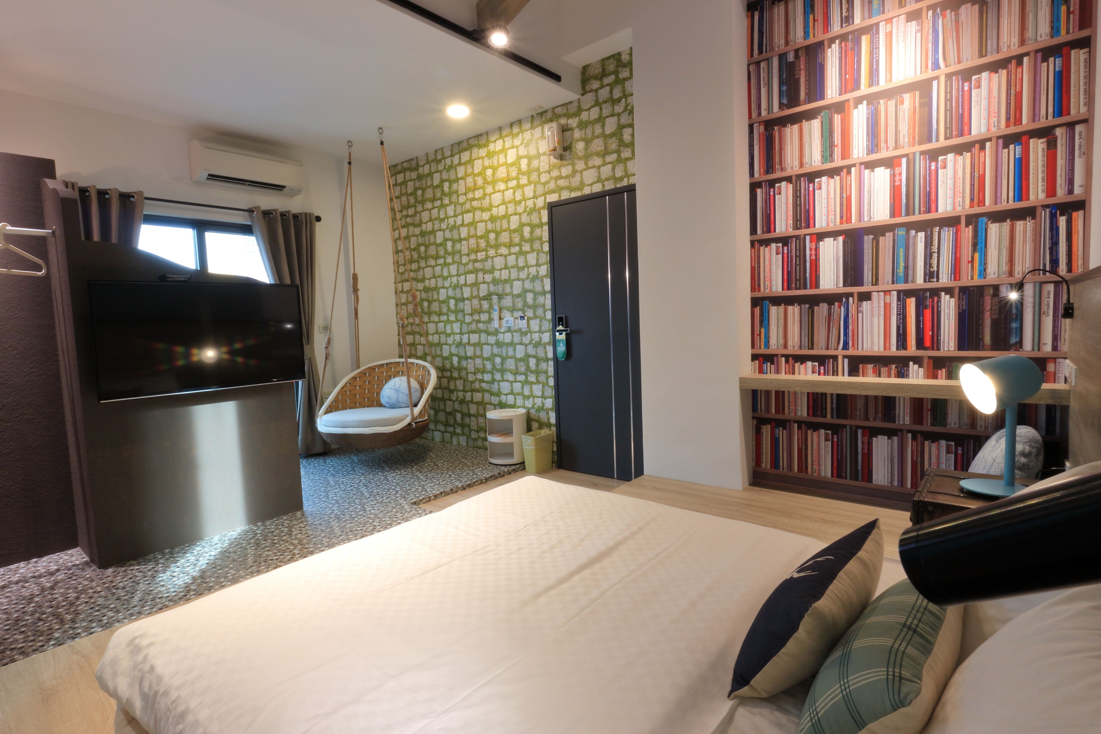 A bedroom with a bed, a bookshelf, a TV, a chair, and a wardrobe.