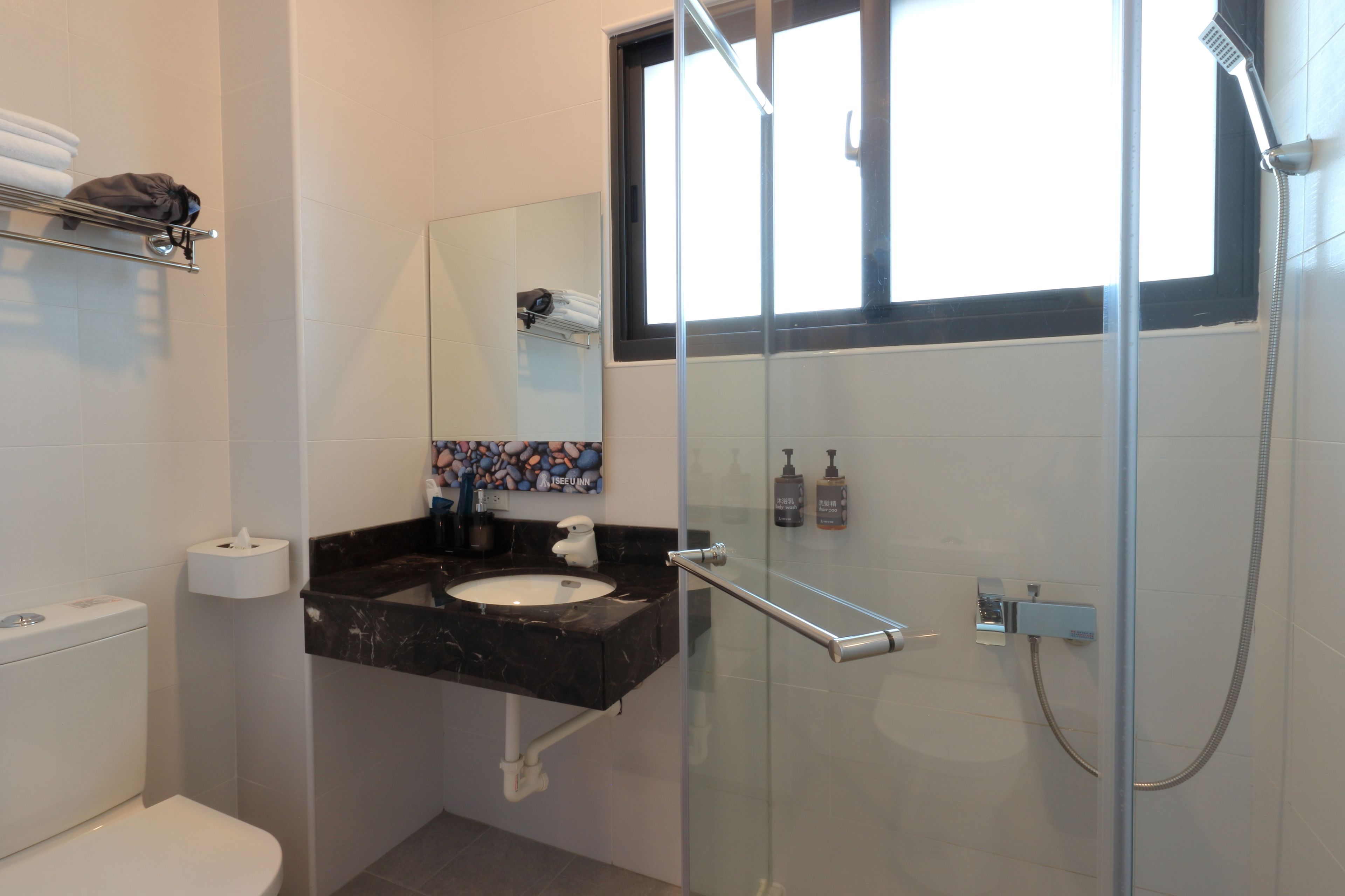 A modern bathroom with a glass-enclosed shower, a black marble sink, and a toilet.
