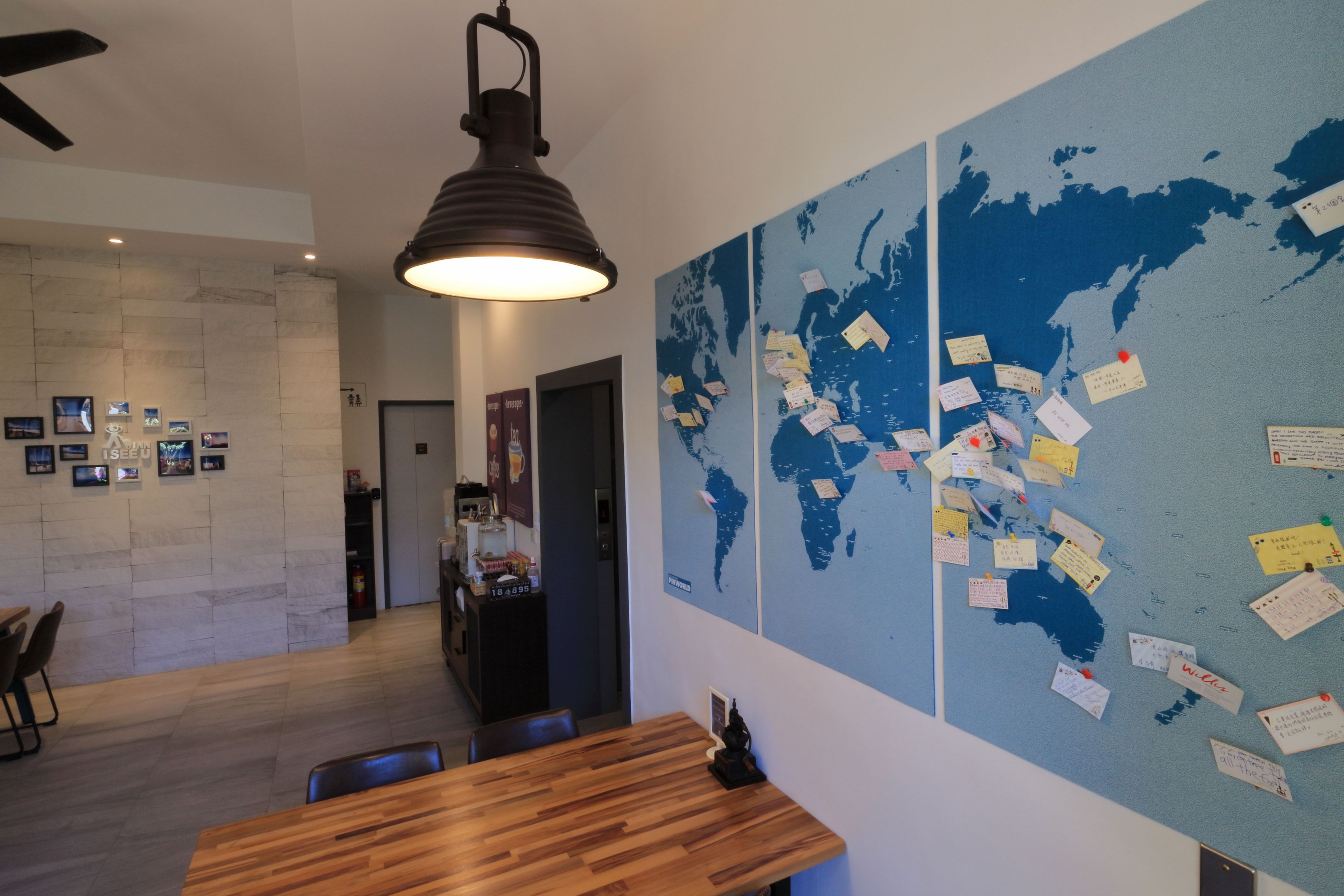 A modern office space with a large world map on the wall, a wooden table, and a hanging lamp.