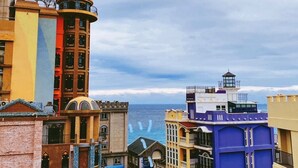 A coastal cityscape with a variety of buildings, including a prominent tower and a lighthouse. - I See U Inn (Xincheng)