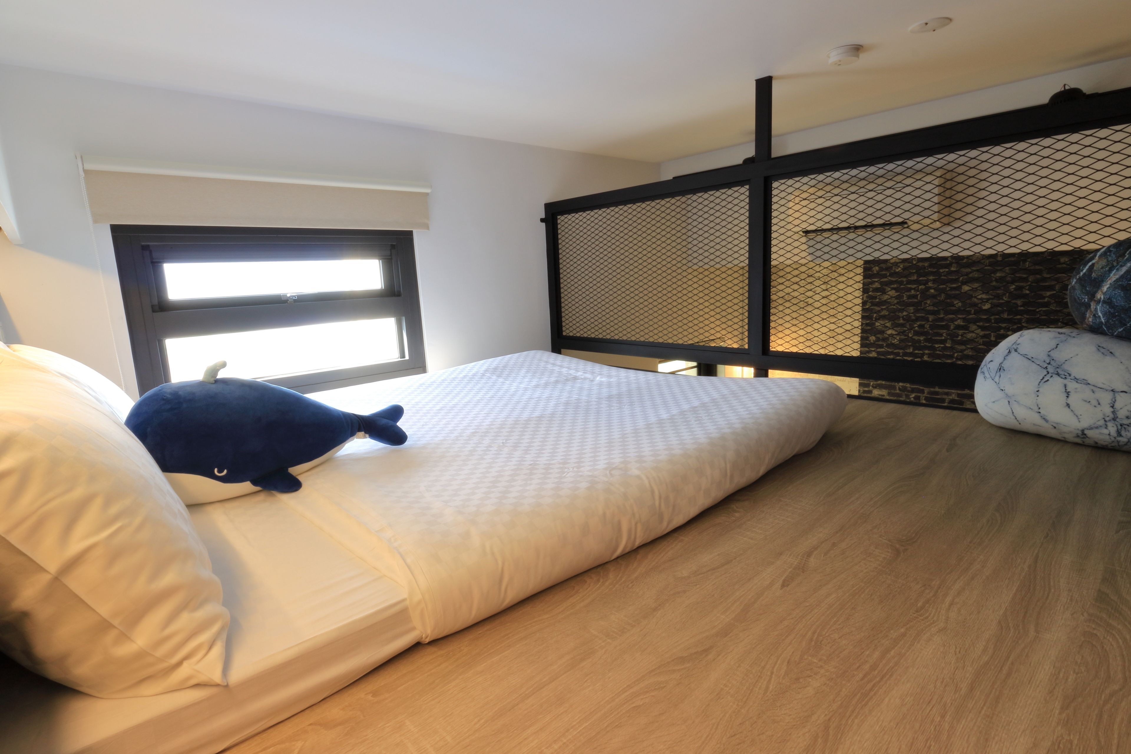 A room with a bed, a window, and a view of a brick wall.