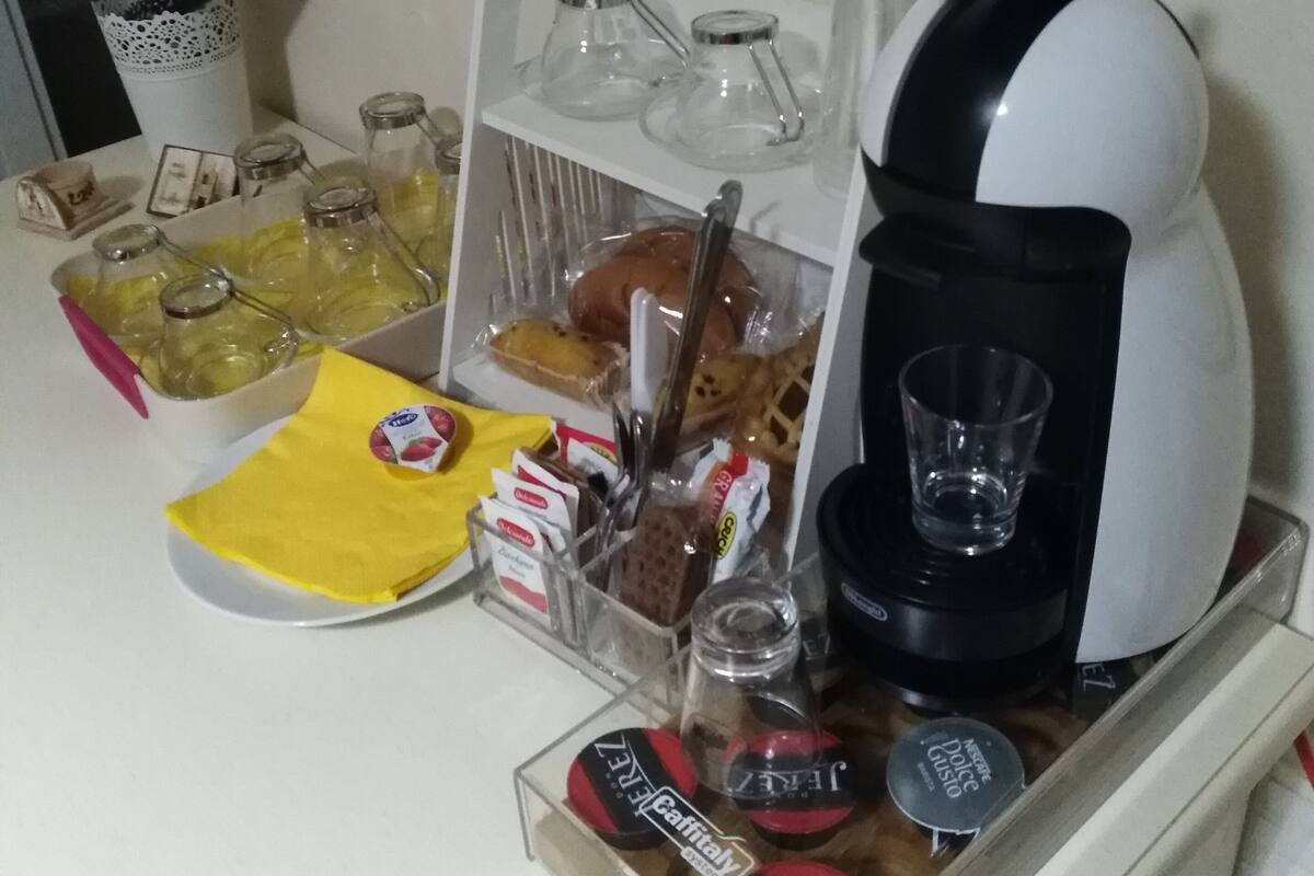 Una kitchenette con una cafetera, un tarro de vidrio y diversos alimentos.