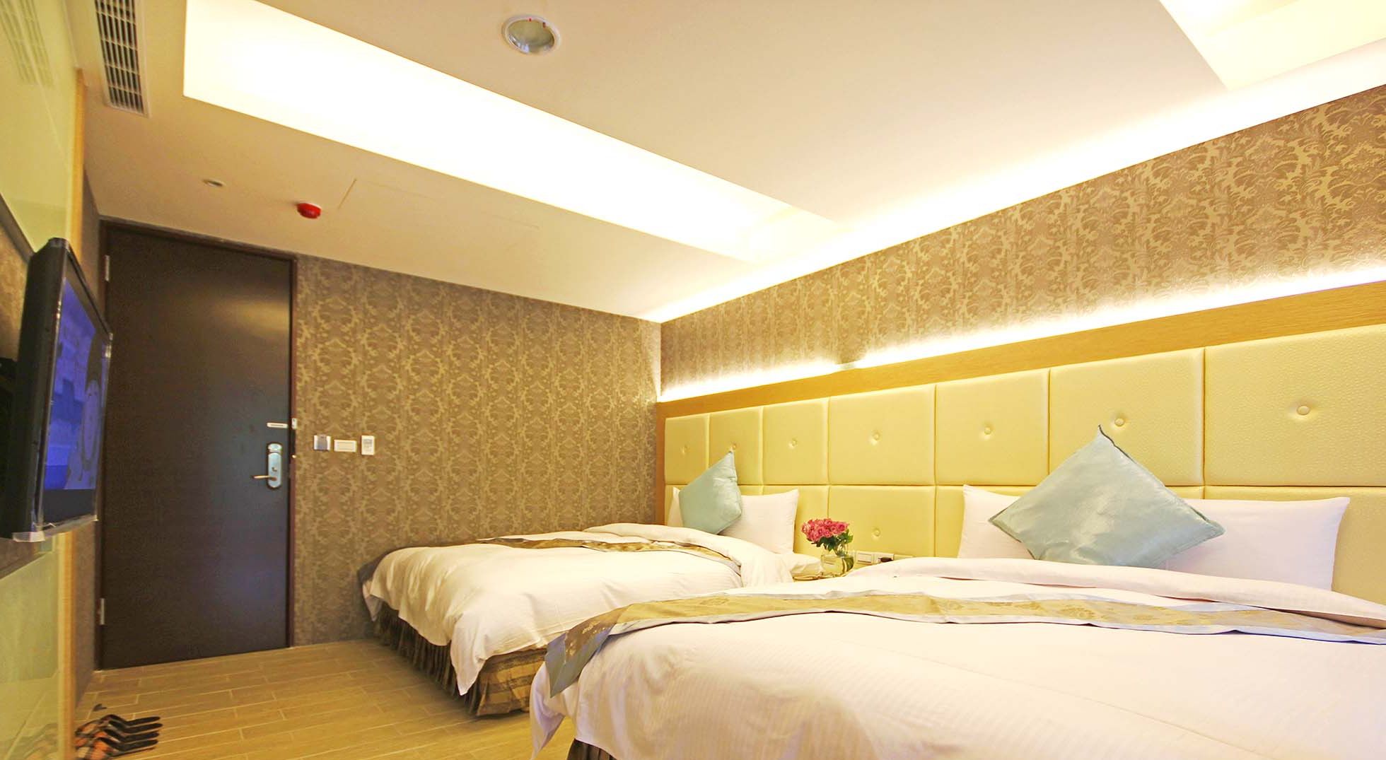 A hotel room with two beds, a television, and a door.