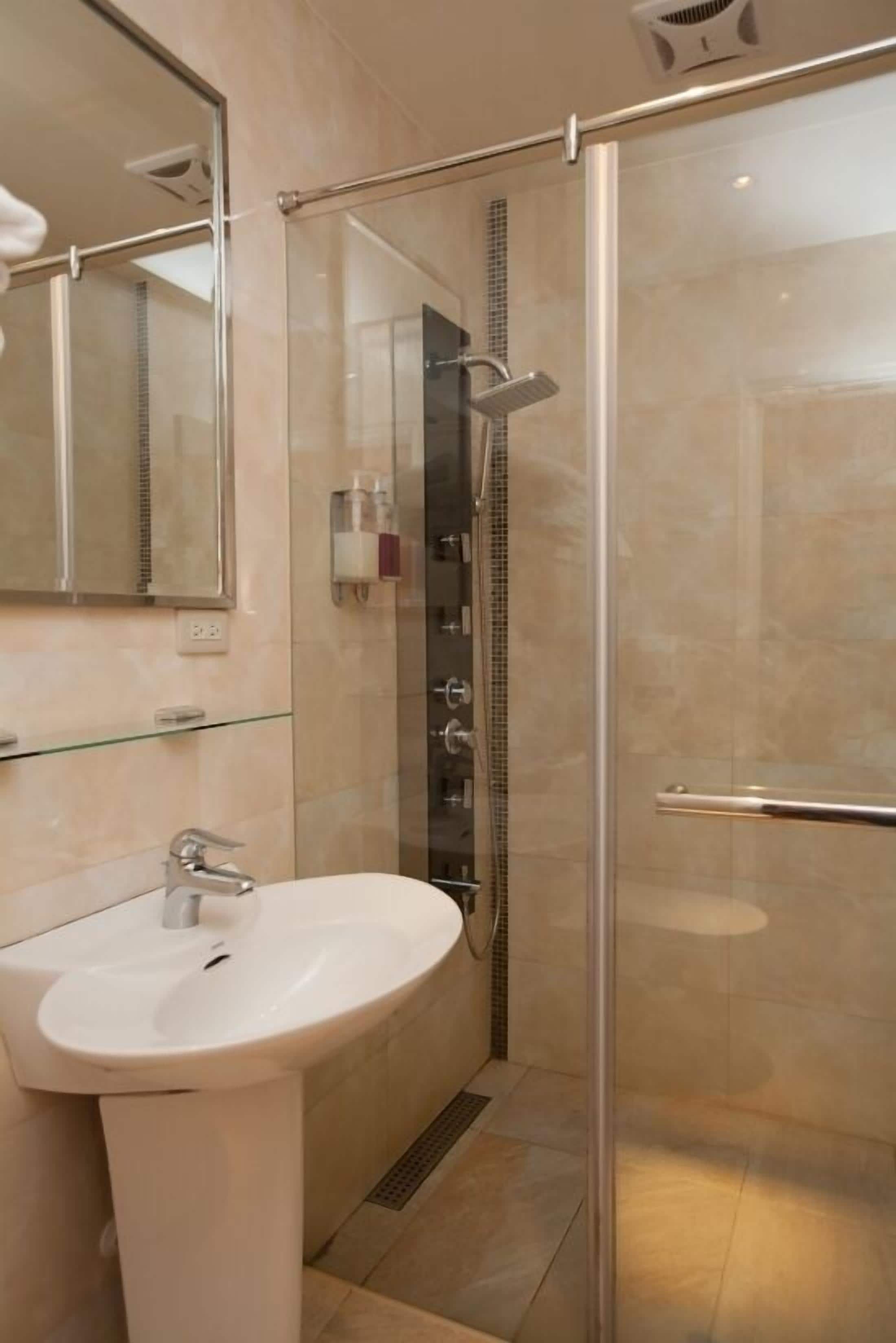 A modern bathroom with a glass-enclosed shower, a white sink, and a mirror above it.