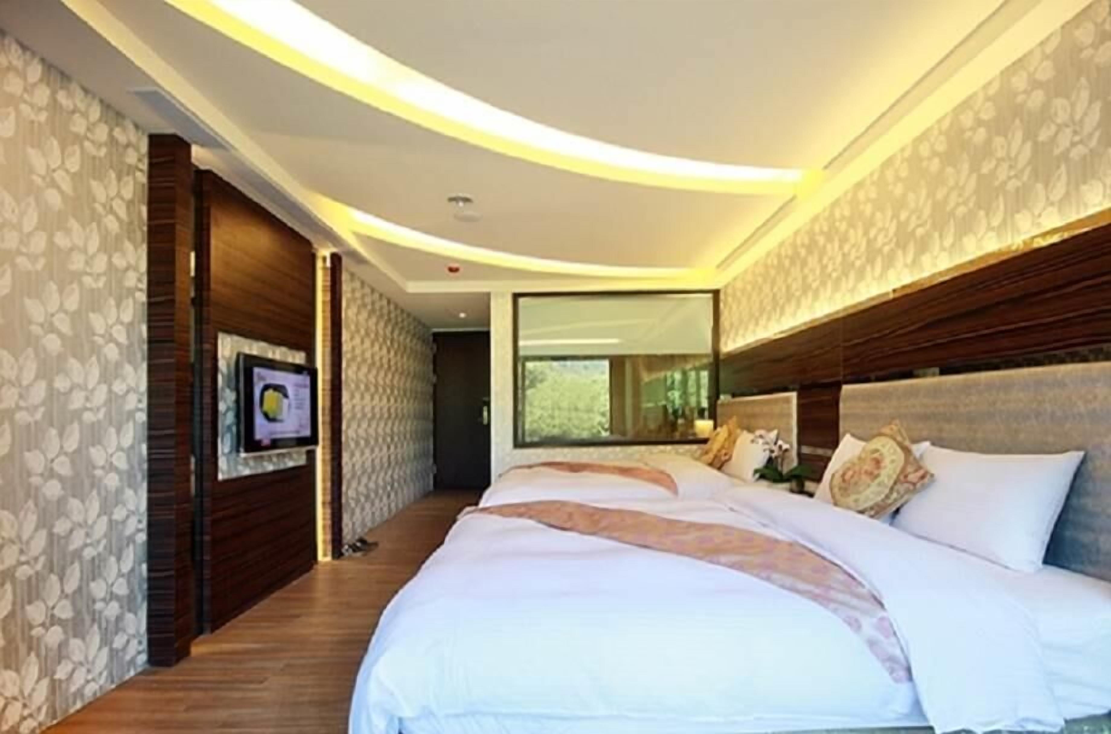 Een moderne slaapkamer met een groot bed, houten lambrisering en een groot raam.