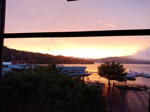 A sunset view from a window overlooking a waterfront with boats, a bridge, and buildings. - Shuian Lakeside Hotel (Yuchi)