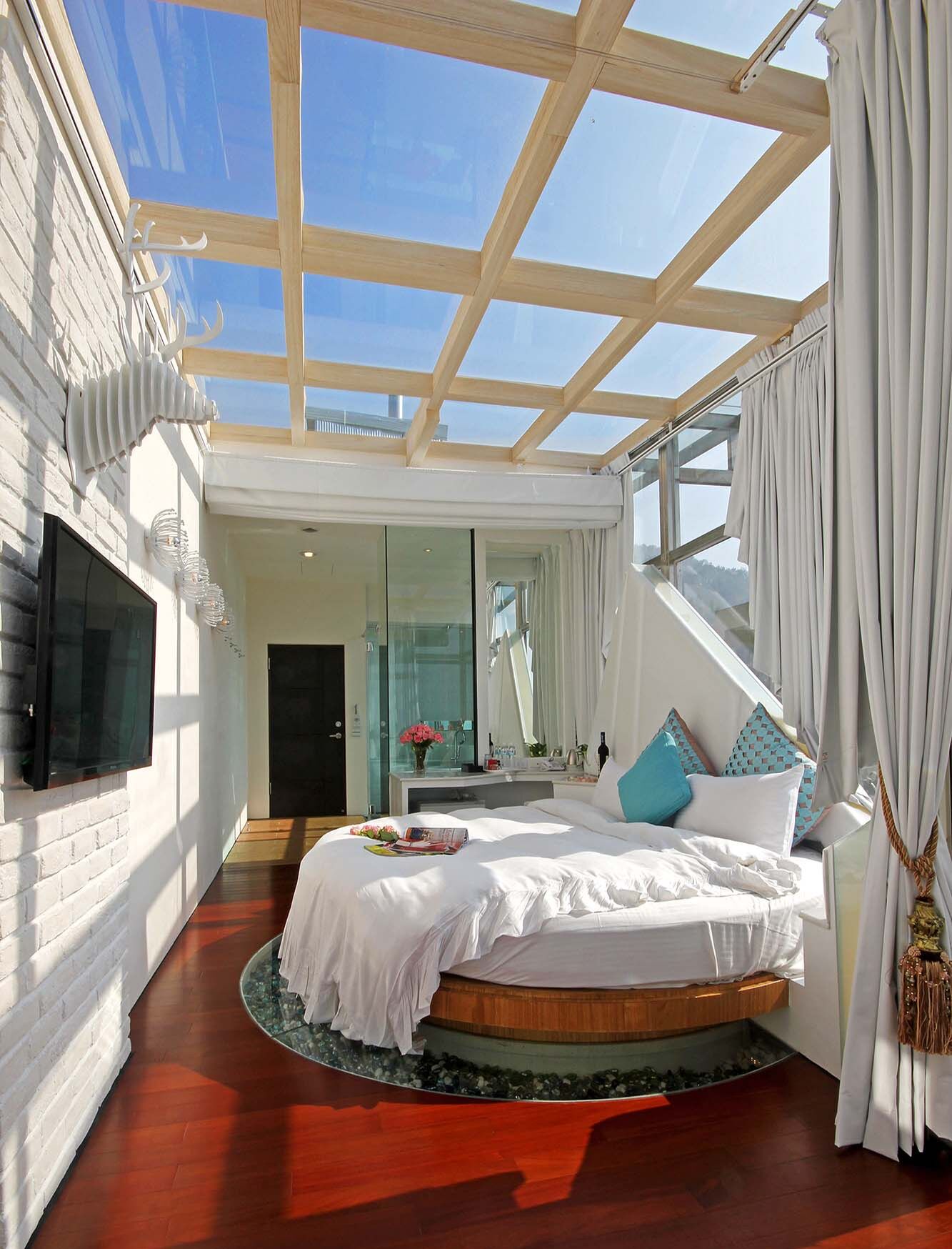 Un dormitorio moderno con tragaluz, cama redonda y vistas al exterior.