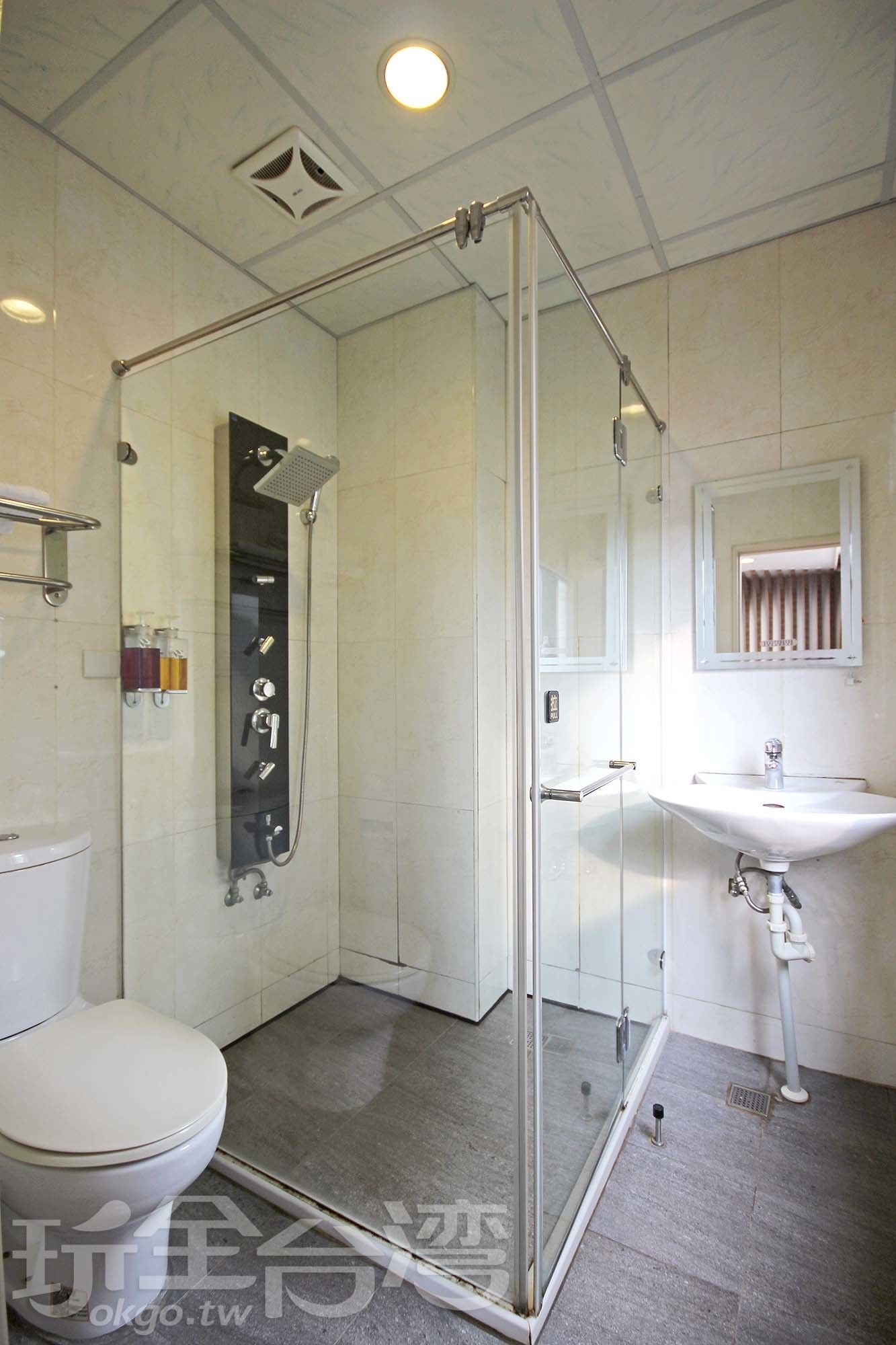 A modern bathroom with a glass-enclosed shower, a toilet, and a sink.