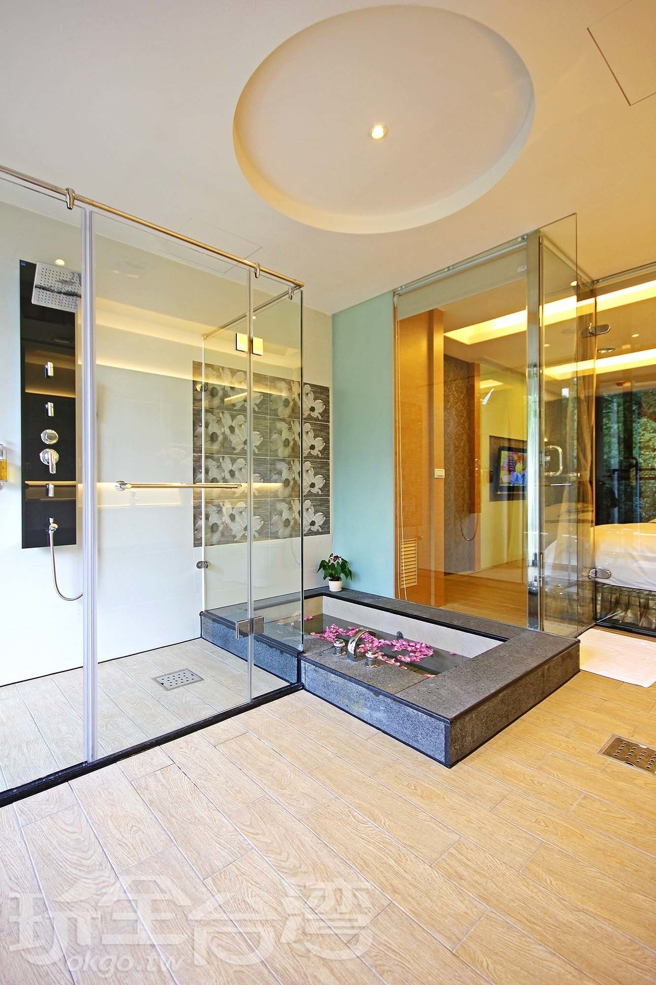 A modern bathroom with a glass shower enclosure, a built-in bench, and a small potted plant.