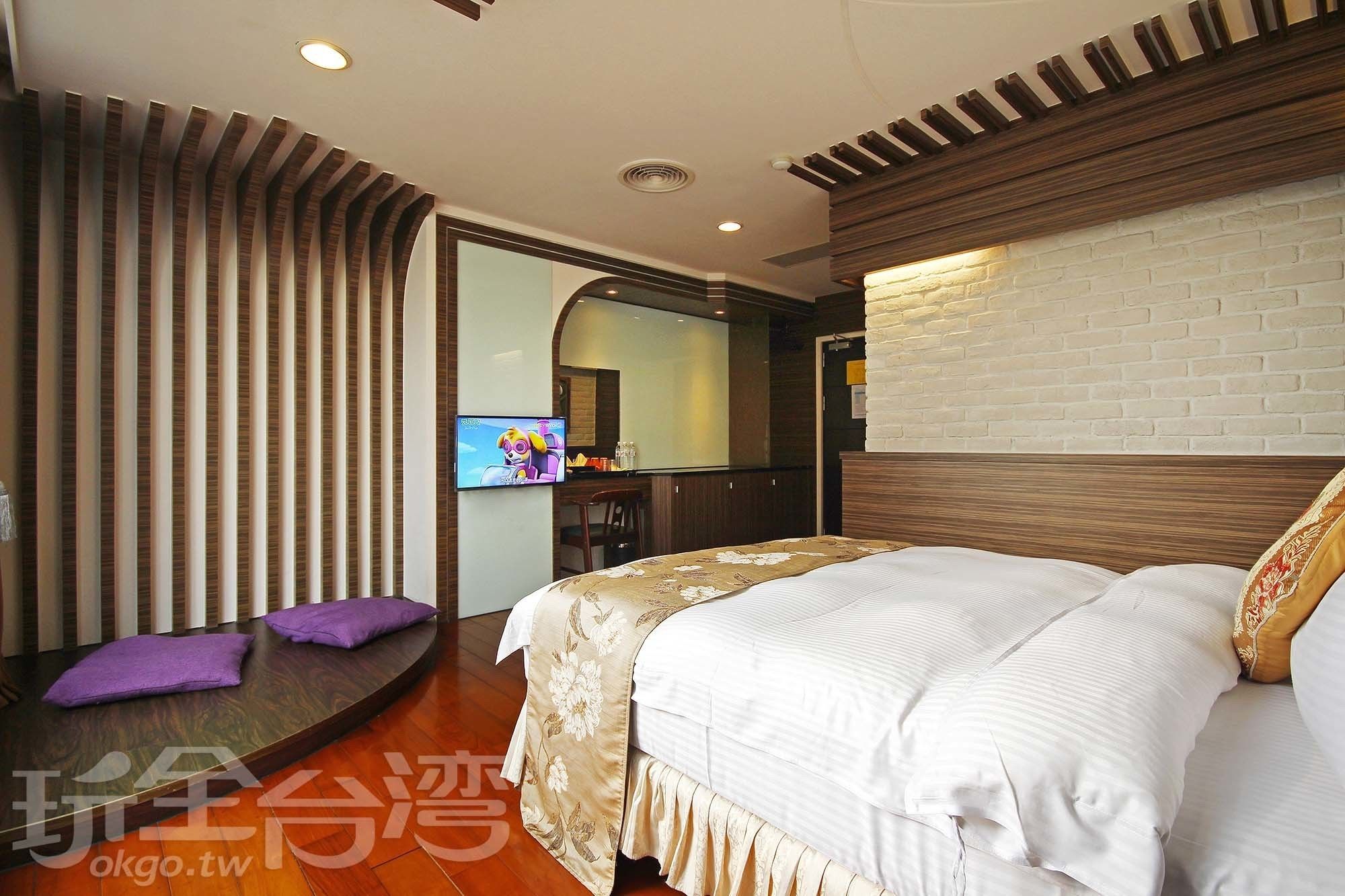 A modern hotel room with a large bed, a TV mounted on the wall, and a wooden floor.