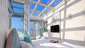 A bedroom with a large skylight, a bed with multiple pillows, a mounted TV, and a view of the sea. - Shuian Lakeside Hotel (Yuchi)