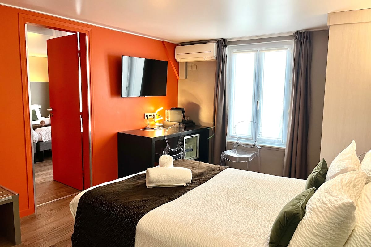 Ein Hotelzimmer mit Bett, Schreibtisch, Fernseher und einem Fenster mit Vorhängen.