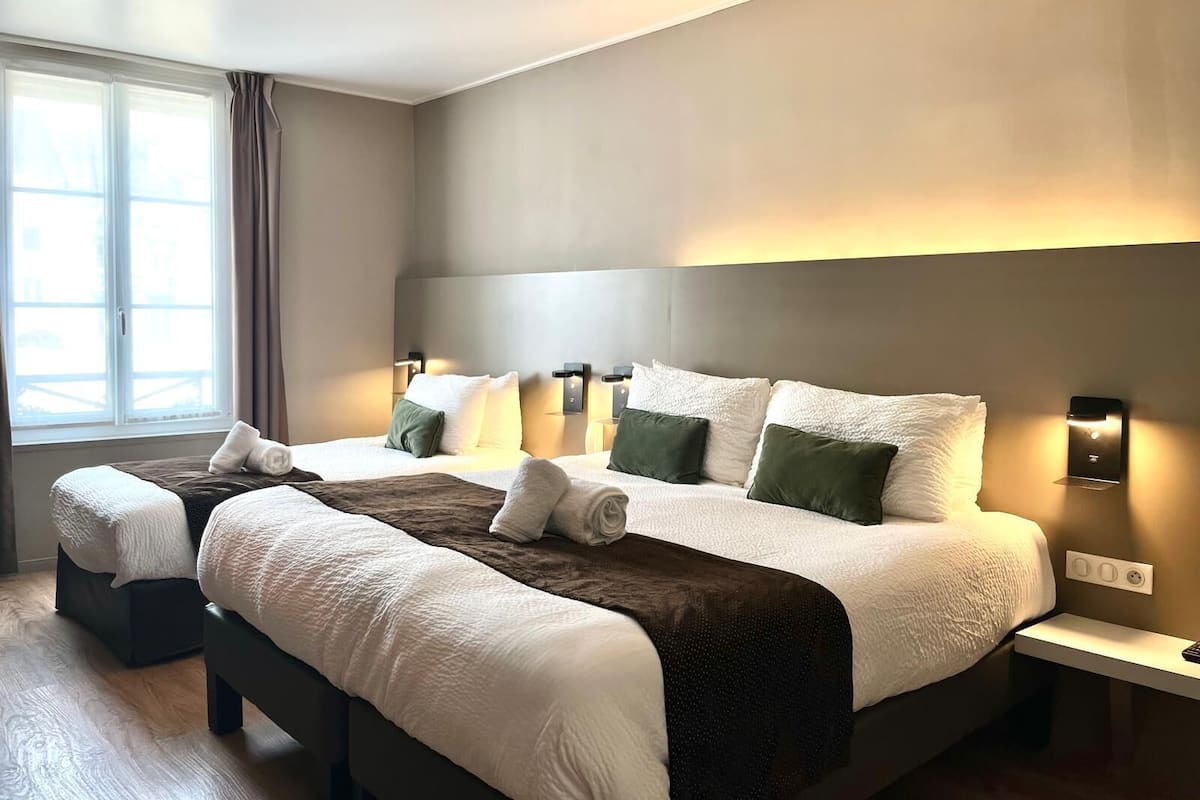 Ein modernes Hotelzimmer mit einem großen Bett, zwei Nachttischen und einem mit Vorhängen versehenen Fenster.