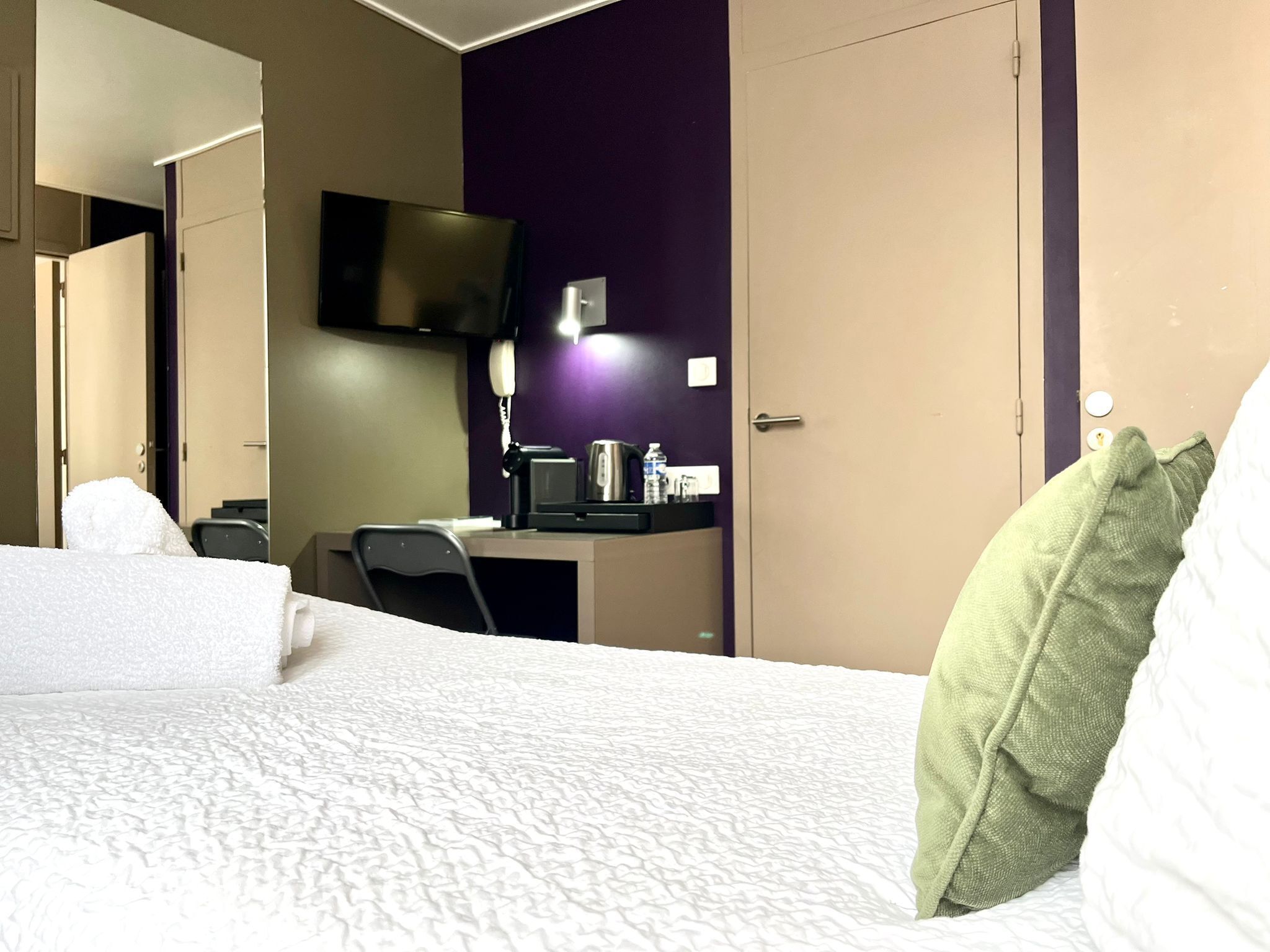 A hotel room with a bed, a desk, a chair, a television, and a telephone.