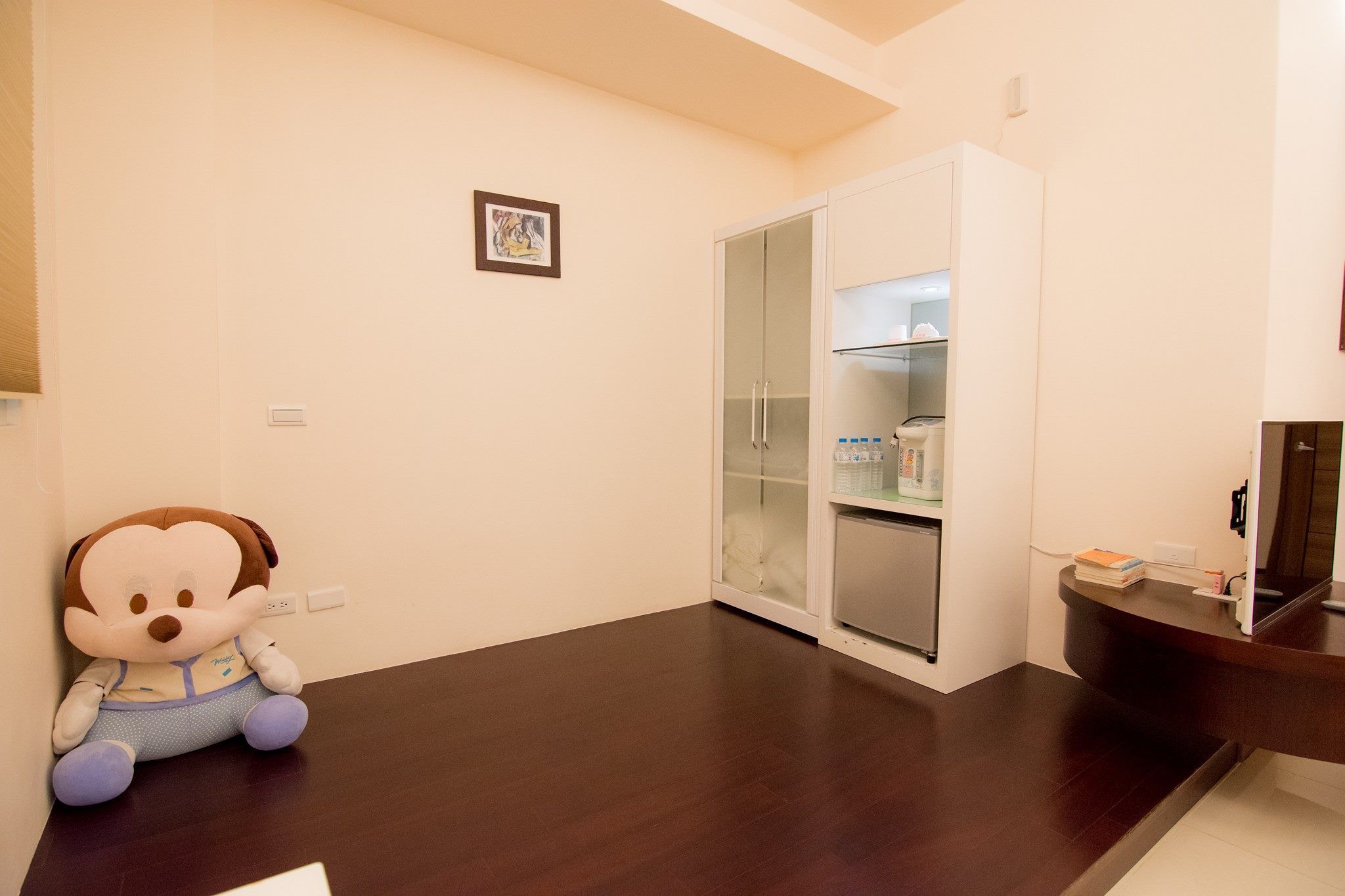 A room with a plush toy, a wardrobe, and a small kitchenette.