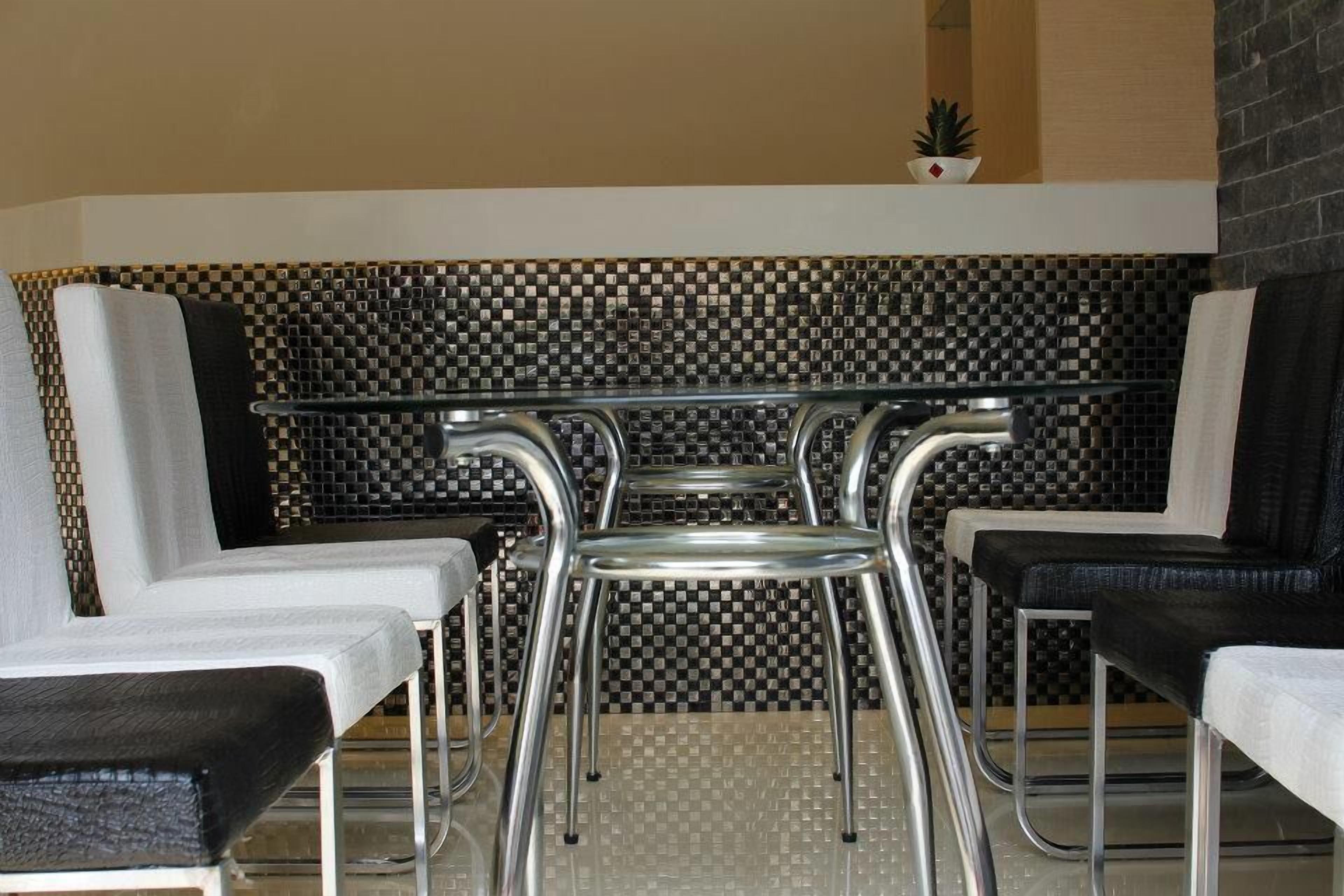 A modern indoor seating area with a glass-top table and metal chairs.