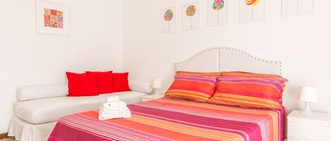 Un dormitorio con cama, sofá y mesita de noche.