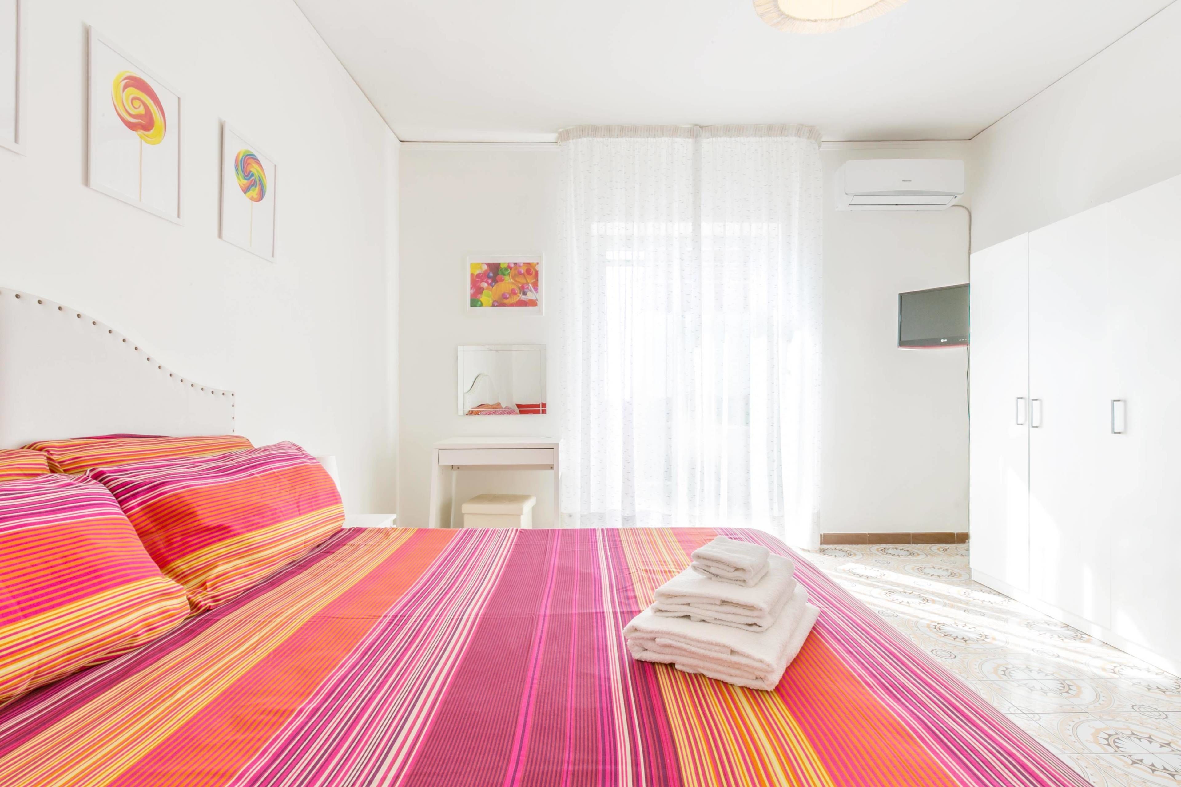 A hotel room with a bed, a desk, a TV, and a wardrobe.