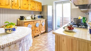 A kitchen with wooden cabinets, a refrigerator, a stove, and a table with a bowl of fruit. - Sorrento 3 bedrooms Sunny Apt with terrace & view (Sorrento)