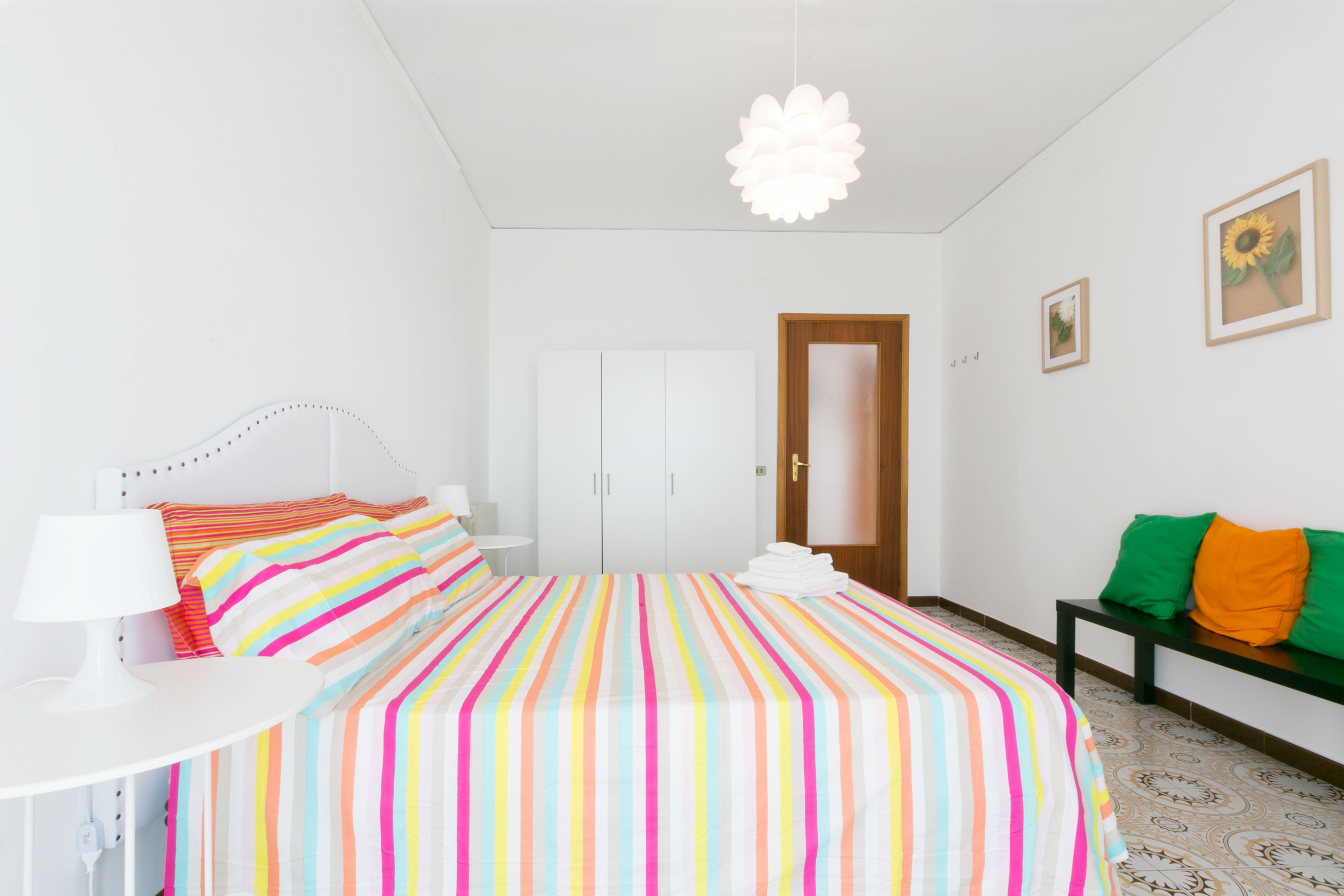 Un dormitorio con cama, escritorio, silla, armario y puerta.