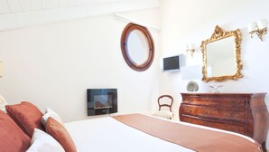 Une chambre à coucher bien rangée, avec un grand lit, une commode, un miroir rond et un téléviseur à écran plat.