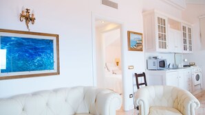 Une pièce comprenant un canapé blanc, une table à manger et un coin cuisine avec des placards et des appareils électroménagers.