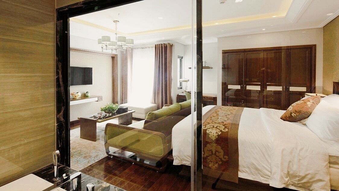 Una habitación de hotel moderna con una cama grande, un área de descanso con sofá y sillones, un escritorio y un armario.
