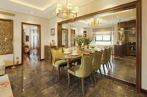 A dining area with a marble floor, a round table, and green upholstered chairs.