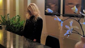 A reception desk with a receptionist, framed artwork on the wall, and potted plants. - Avra Hotel (Katerini)
