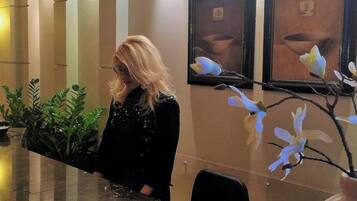 A reception desk with a receptionist, framed artwork on the wall, and potted plants.