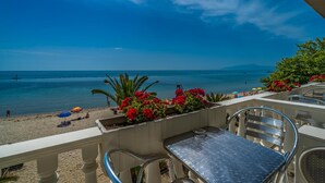 A balcony with a view of the beach and sea, outdoor seating, and potted plants. - Avra Hotel (Katerini)