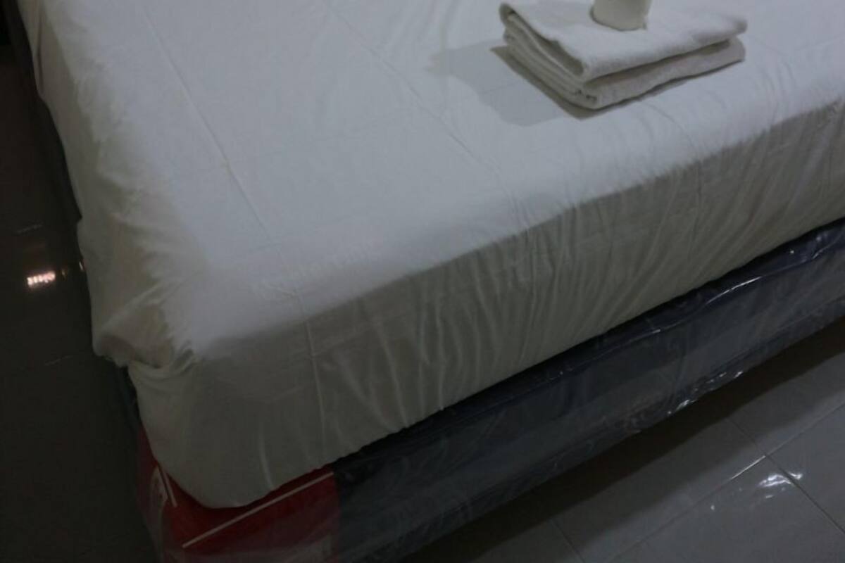 Una cama bien tendida con sábanas blancas y una toalla doblada al lado.