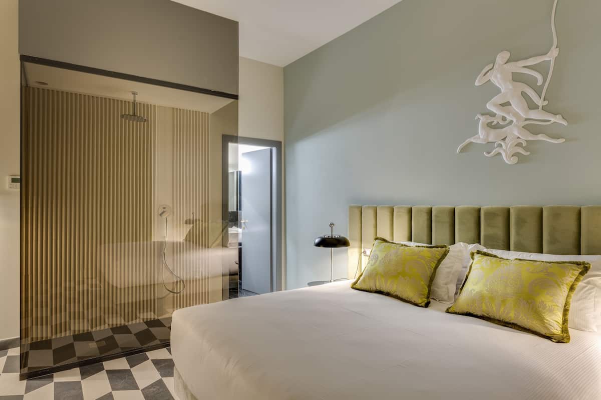 A bedroom with a large bed, two decorative pillows, a headboard, and a wall art piece.