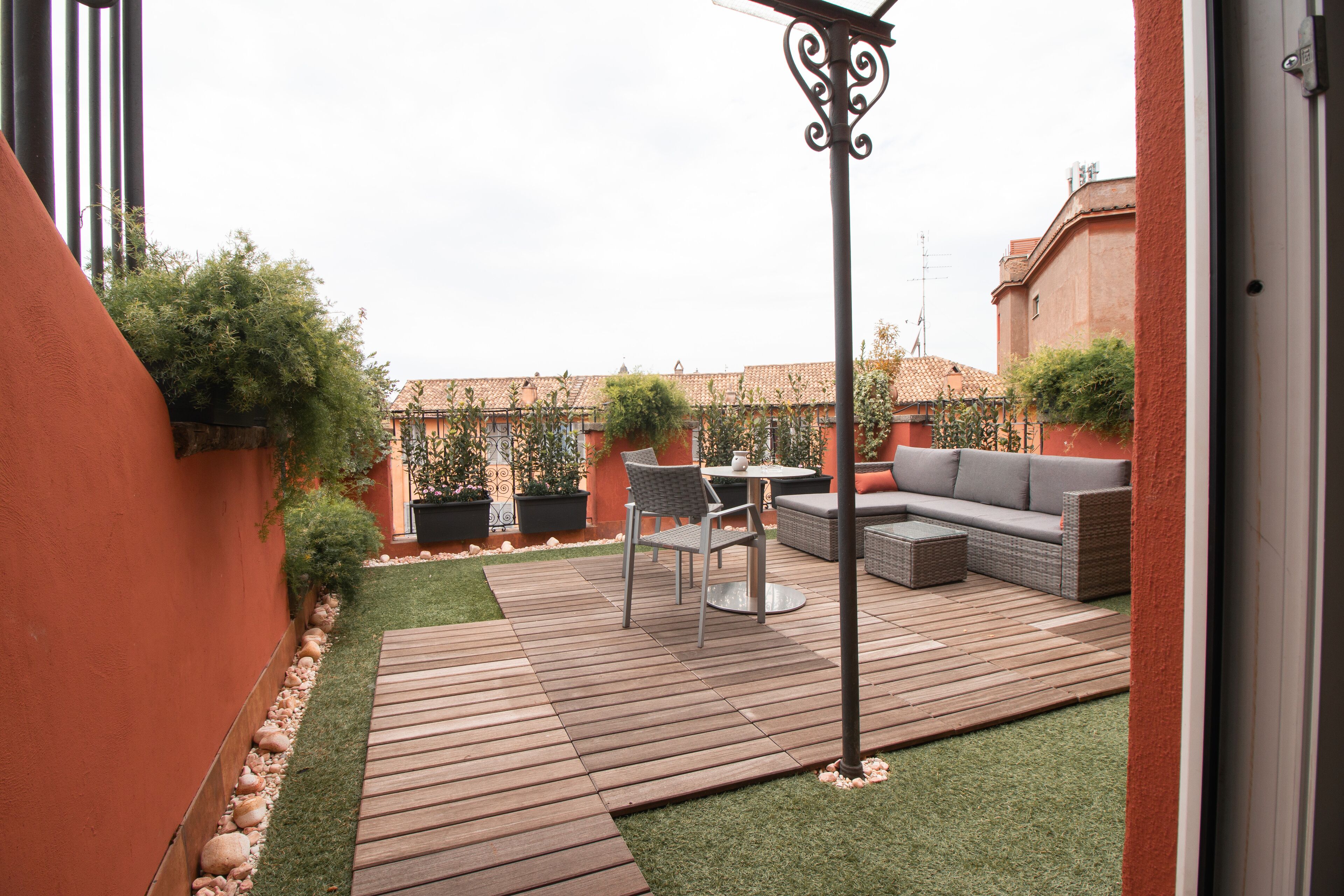A patio with a wooden deck, a round table, and a sofa.