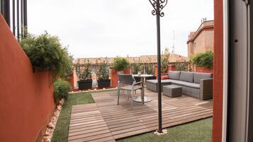 A patio with a wooden deck, a round table, and a sofa.