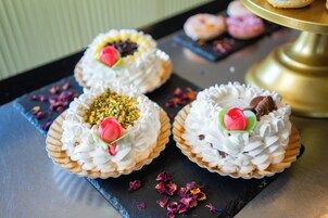 Three decorated cakes on a slate serving board with a gold cake stand in the background.