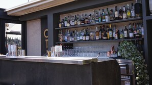 A bar area with multiple shelves of liquor bottles, glasses, and a bar counter. - Otivm Hotel (Rome)