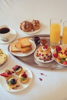 A breakfast tray with toast, pancakes, fruit, and juice.