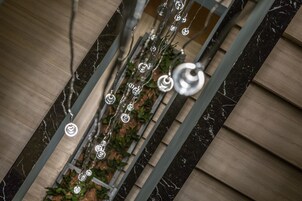 A modern interior with a marble floor, metal railings, and hanging decorative elements.