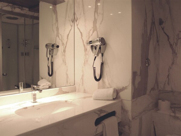 A bathroom with a marble vanity, a hairdryer mounted on the wall, and a towel rack.