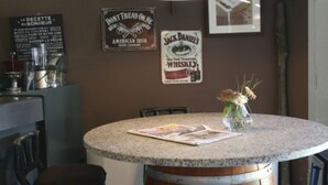 A bar area with a round table, bar stool, and a decorative barrel. - Cors Hotel (Biguglia)