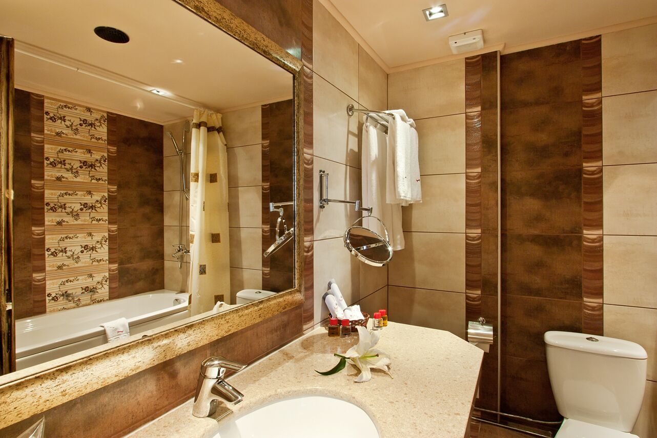 Un baño moderno con un espejo grande, una bañera, una ducha y un inodoro.